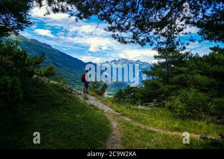 Donna escursionista e una vista verso Avrieux e Modane, nella valle di Maurienne, Francia Foto Stock
