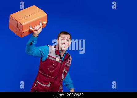 Ambulanza medico uomo in un vestito da lavoro e con un box in mano in posa su uno sfondo blu Foto Stock