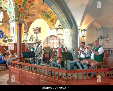 In costume da liederhosen bavarese tradizionale, la band oompah dell'Hofbrauhaus di Monaco intrattiene i commensali con la tipica musica bavarese. Foto Stock