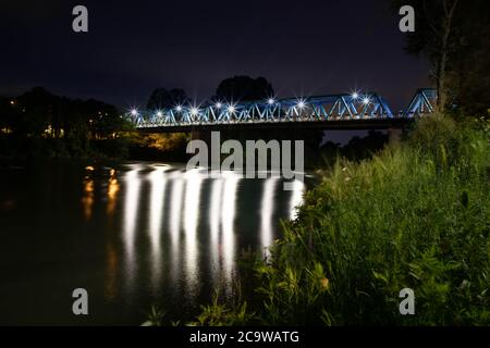 San Dona di Piave e il Ponte della Vittoria illuminano la sera con una riflessione sul Piave visto dal basso. Foto Stock