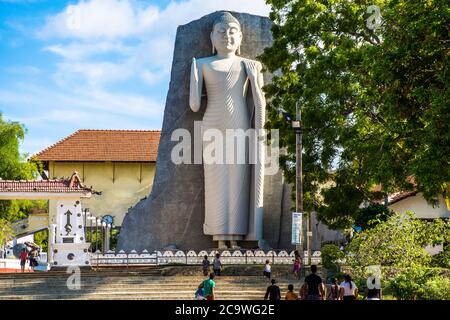 Un'enorme statua di buddha appoggiata contro una roccia vicino al tempio di Sir Lanka. Foto Stock