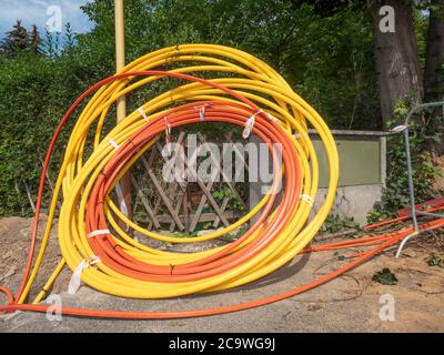 Bobine di involucri in plastica, cavo dati inserito in trincea sotterranea. Cavo in fibra ottica per Internet veloce. Area case residenti. Foto Stock