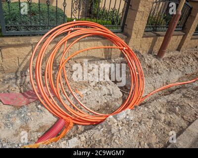 Fascio cavo in fibra arancione su un cantiere. Costruzione di linee di cavi metallici e in fibra ottica di collegamento alla rete di comunicazione Foto Stock