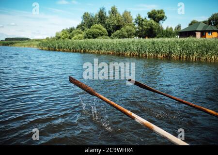 gli atleti in vacanza sono impegnati nel canottaggio, nuotatori su remi di legno colpire l'acqua, spruzzando un sacco di gocce intorno Foto Stock