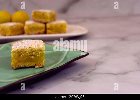 Quadrati di limone cotti in casa, barrette di limone, su sfondo di marmo minimo con spazio di copia Foto Stock