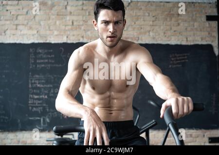 Uomo che usa la bicicletta da ginnastica in palestra. Fitness maschile utilizzando la moto d'aria per l'allenamento cardio alla palestra di allenamento funzionale Foto Stock