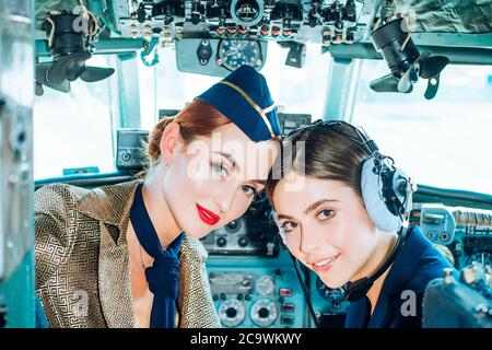 Ritratto di due donne sorridenti piloti. Bella giovane donna sorridente pilota seduto in cabina di aerei moderni. Stewardess e istruttore di volo in un Foto Stock