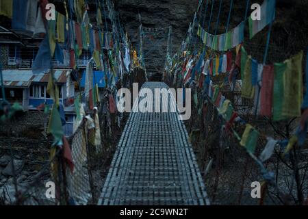 Chame sospensione ponte colorato buddista preghiera bandiere sul fiume Marshyangdi, circuito Annapurna, Nepal Foto Stock