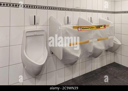 Dietikon, Zurigo - Svizzera - 26 maggio 2020: I due orinatoi centrali sono chiusi e tappati con plastica per garantire la distanza nella toilette pubblica Foto Stock