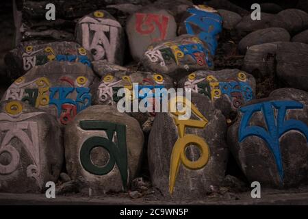 Iscrizioni religiose colorate in pietre, villaggio di montagna Chame, trekking circuito Annapurna, Nepal Foto Stock