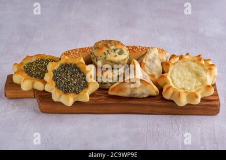 Pasticceria, fatayer o samosa, manaqeesh con zaatar e formaggio bianco su tavola di legno Foto Stock