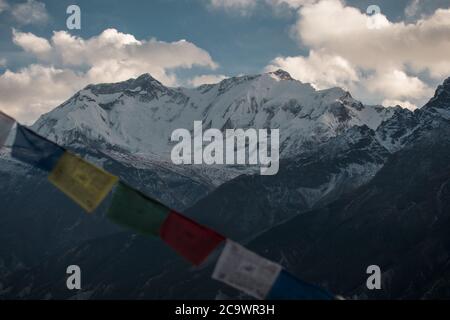 Bandiere buddiste di preghiera nelle montagne nepalesi innevate, circuito di Annapurna, Himalaya Foto Stock