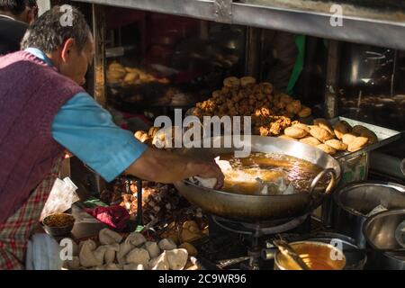 Uomo nepalese anziano che cucina tradizionale fritto cibo di strada, Pokhara dicembre 2019 Foto Stock