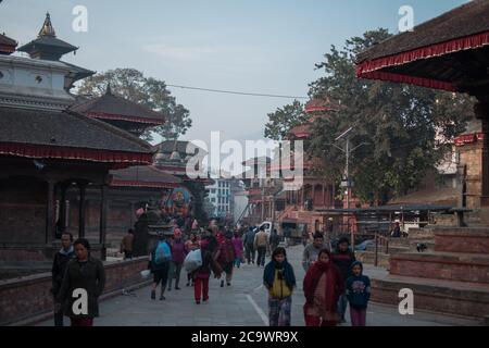 Persone che camminano attraverso una piazza centrale piena di templi a Kathmandu, Nepal Foto Stock