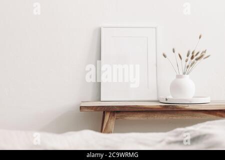 Mockup cornice bianco ritratto su panca in legno d'epoca, tavolo. Moderno  vaso in ceramica bianca con erba secca di Lagurus ovatus e vassoio in marmo  beige sfocato Foto stock - Alamy