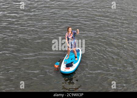 Una donna paddle boarder visto fuori sul fiume Tamigi a Hampton Court quando il tempo raggiunge 30°. Foto Stock