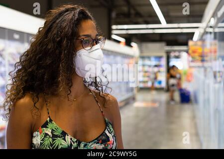 Giovane donna brasiliana shopping nel supermercato con maschera. Nuovo concetto di normalità. Foto Stock