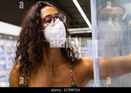 Giovane donna brasiliana shopping nel supermercato con maschera. Nuovo concetto di normalità. Foto Stock