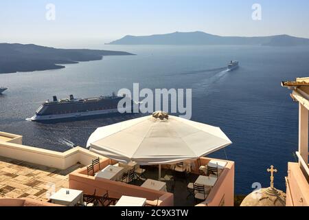 Oia, Santorini, Grecia, 21 agosto 2013: Un caffè accogliente con una splendida vista sulle montagne, il mare blu e le navi da crociera in arrivo Foto Stock