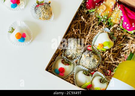 Confezione regalo piatta con fragole immerse a mano, rose fresche e una bottiglia di liquore Foto Stock