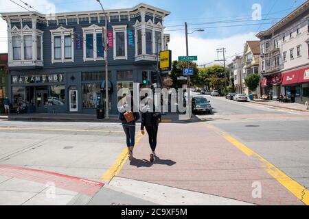 Le donne aspettano di attraversare la strada ad un incrocio nel quartiere Noe Valley di San Francisco, CA, USA. Foto Stock