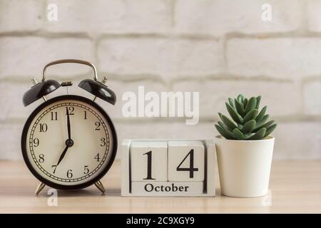 Ottobre 14 su un calendario di legno accanto alla sveglia, la data del mese di autunno. Foto Stock