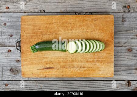 Primo piano di zucchine a fette su tagliere di legno Foto Stock