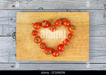 amore cuore composizione di pomodoro su sfondo di legno Foto Stock