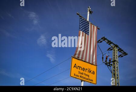 Amerika, Germania. 01 agosto 2020. Un segno del toponimo dell'America è appeso sotto una bandiera degli Stati Uniti nel villaggio nella Valle del Mulde. Non si sa esattamente come l'attuale parte della città di Penig abbia preso il suo nome. Credit: Hendrik Schmidt/dpa-Zentralbild/ZB/dpa/Alamy Live News Foto Stock