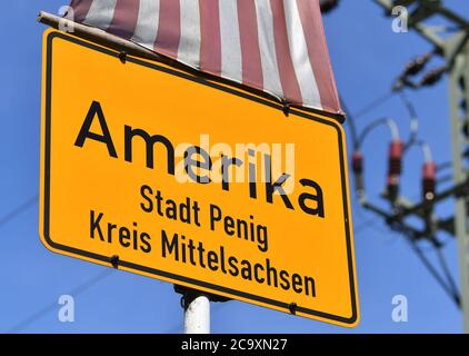 Amerika, Germania. 01 agosto 2020. Un segno del toponimo dell'America è appeso sotto una bandiera degli Stati Uniti nel villaggio nella Valle del Mulde. Non si sa esattamente come l'attuale parte della città di Penig abbia preso il suo nome. Credit: Hendrik Schmidt/dpa-Zentralbild/ZB/dpa/Alamy Live News Foto Stock