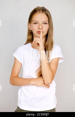 Ritratto della ragazza teenager che tiene il dito vicino alle labbra e showint mantenere il segno del silenzio Foto Stock