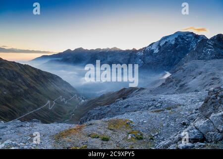Passo dello Stelvio con montagne innevate e una strada tortuosa nella valle Foto Stock