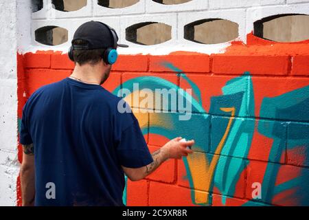 Artista di strada che dipinge un graffiti colorato su una parete bianca Foto Stock