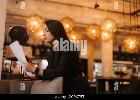 Ispettore donna professionista in un ristorante di lusso moderno che scrive in documenti cartacei. Foto Stock