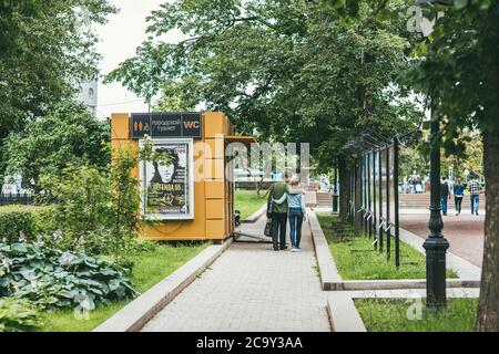 Mosca, Russia - 7 LUGLIO 2017: I giovani e le donne camminano abbracciando il sentiero per il parco oltre i banner con foto alla mostra fotografica della città Foto Stock