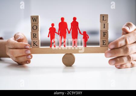 Coppia felice la protezione di equilibrio tra lavoro e vita familiare e carta ritagliata su altalena Foto Stock