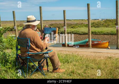 Un artista pittura en plein air sulla costa del Norfolk. Foto Stock