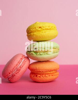 stack di macaron al forno su sfondo rosa, delizioso dessert a base di farina di mandorle, primo piano Foto Stock