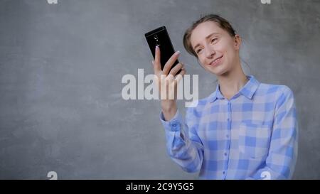 Comunicazione, stile di vita, concetto di tecnologia online. Donna positiva in camicia plaid con smartphone, con video chat, conferenza online, lavoro Foto Stock