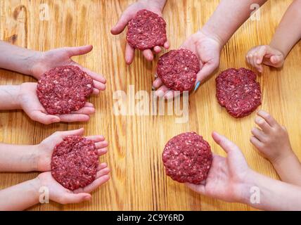 i bambini tengono in mano polpettine di carne macinata cruda, vista dall'alto Foto Stock