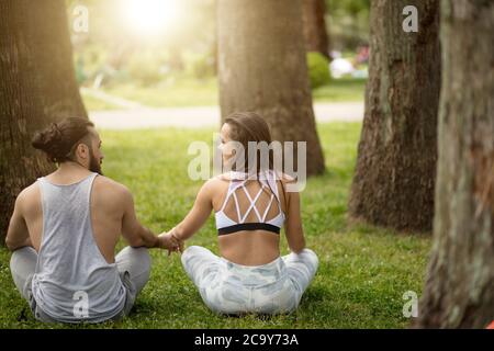 Professional trainer di yoga e la sua femmina studente a condurre i loro outdoor training in un verde parco della città. Il concetto di uno stile di vita sano. Foto Stock