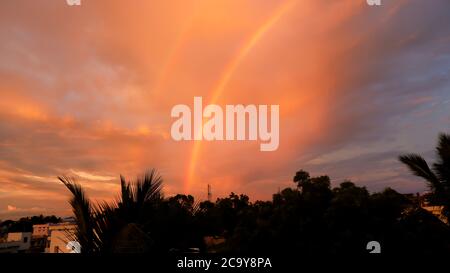 un bellissimo doppio arcobaleno e aquiloni volanti in cielo in serata Foto Stock