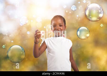 Afro gioco bambino con bolla di sapone all'aperto con una giornata di sole Foto Stock