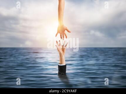 L'uomo d'affari sta annegando nell'oceano e riceve l'aiuto Foto Stock