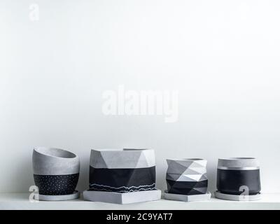 Piantatrici moderne e geometriche in calcestruzzo vuote su ripiano bianco isolato su fondo bianco con spazio per la copia. Bel colore nero e argento verniciato c Foto Stock