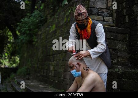 Kathmandu, Nepal. 3 agosto 2020. Un prete indù rasa i capelli di un devoto durante il festival. Durante Janai Purnima, conosciuto anche come il festival del Sacro filo o il festival di Rakshya Bandhan, gli uomini indù, specialmente i Brahmans e Chettris, eseguono il loro cambio annuale di Janai, i fili sacri indossati attraverso il petto o legati intorno al polso. Credit: SOPA Images Limited/Alamy Live News Foto Stock