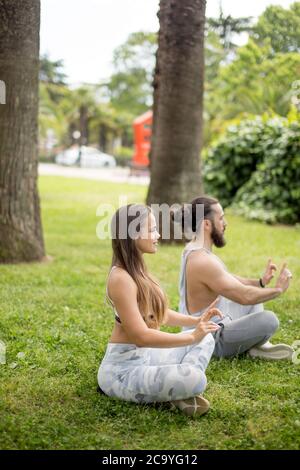 Professional trainer di yoga e la sua femmina studente a condurre i loro outdoor training in un verde parco della città. Il concetto di uno stile di vita sano. Foto Stock