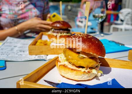 Mangiare hamburger in un evento sociale con gli amici insieme in un ristorante all'aperto su una tavola Foto Stock