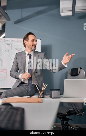 Bell'uomo seduto sul tavolo in ufficio Foto Stock