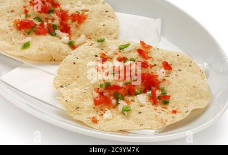 Spuntini Indiani, cracker dal Mung/URAD fritti o arrostiti o papad, un contorno a pranzo e a cena. Servito in un cestino di canna / piatto Foto Stock